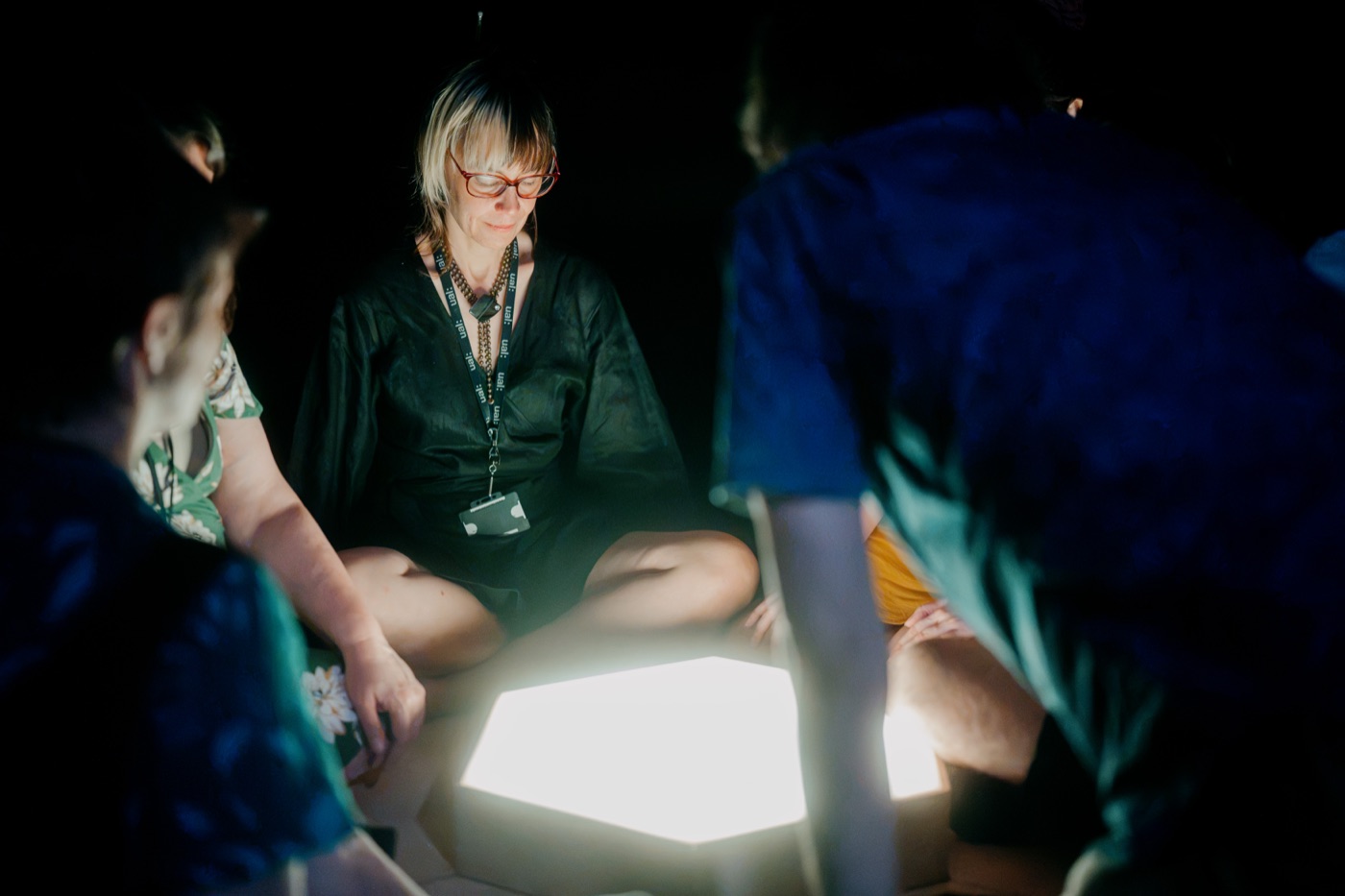 Participants seated in a circle around the glowing central tile during the ritual